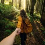 woman in brown jacket standing in forest during daytime